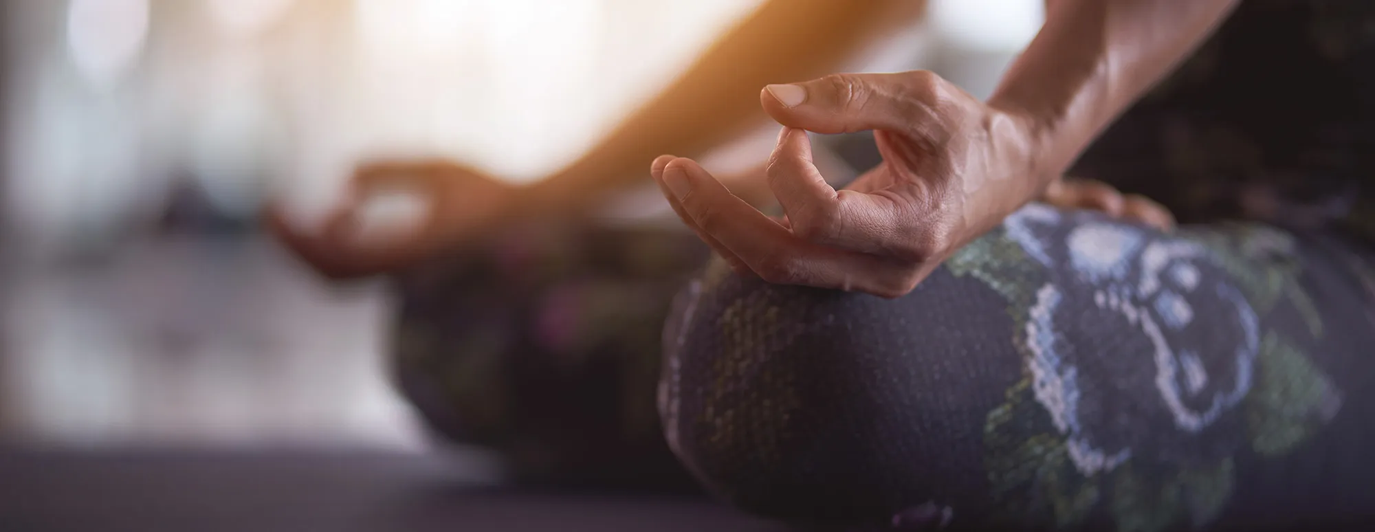 Woman in warrior pose in a sunlit yoga studio